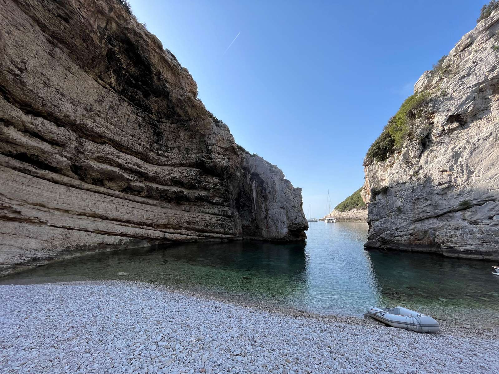 Kiesstrand und Felsentor der Bucht Stiniva mit Dinghy